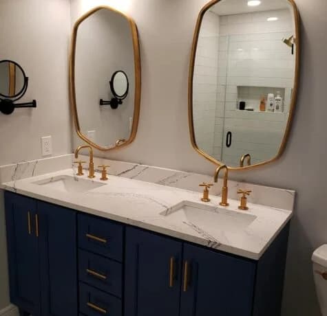 Navy double vanity with brass faucets, brass cabinet pulls, marble-look quartz counter, and brass-framed mirrors in a Foreverbuilt bathroom remodel in NJ