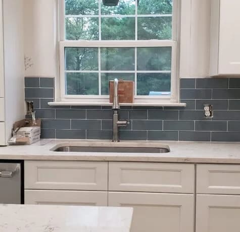 Completed Foreverbuilt kitchen sink wall with white cabinets and a blue glass tile backsplash