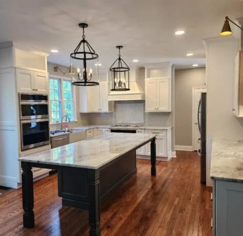 Mercer County kitchen remodel by Foreverbuilt with a furniture-style island on turned legs, marble-look quartz top, white perimeter cabinets, and black lantern pendants
