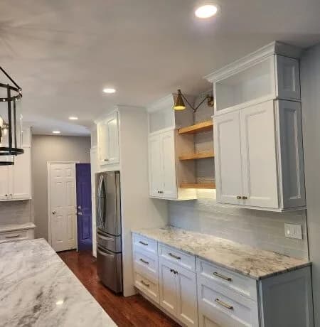 Completed Foreverbuilt kitchen with white shaker cabinets, open corner shelves, and marble-look counters