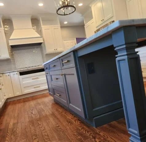 Completed Foreverbuilt kitchen with a navy island, white range hood, and wood floors